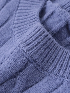 Dettaglio macro del maglione blu a trecce con scollo a costine e texture spessa morbida