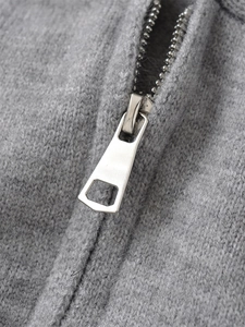 Close-up of the silver metal zipper and smooth grey knitted fabric on the hoodie