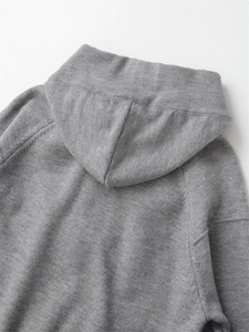 Detail of the gray knit hoodie fabric with a hooded collar and soft heathered texture