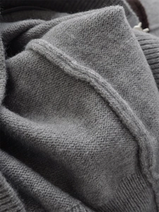 Detailed macro shot of grey knitted hoodie fabric showing soft wool texture and ribbing