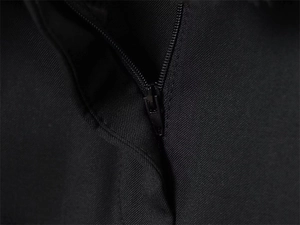 Dettaglio macro della cerniera in metallo nero su pantaloni in tessuto liscio