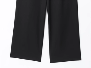 Dettaglio dei pantaloni neri a gamba larga che mostra la trama e la cucitura dell'orlo