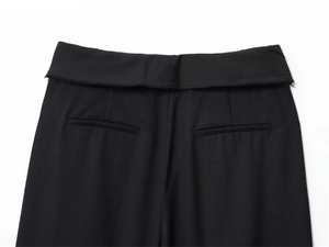 Dettaglio dei pantaloni a vita alta con bordo a taglio vivo e tasche a filetto sul retro