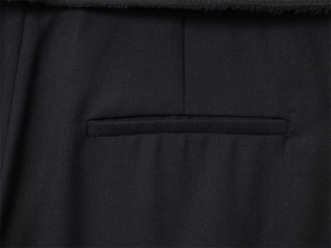 Dettaglio del tessuto twill nero con tasca a filetto e bordi con frange alla moda