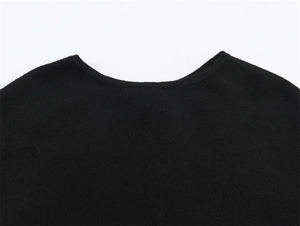 Detailed close-up of a high-quality black knit poncho showing the fine fabric texture