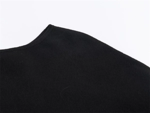 Close-up of the round neckline and knitted texture of a black women's chic poncho jacket