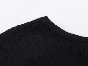 Close-up of black knitted poncho fabric showing soft wool texture and fine craftsmanship