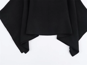 Close-up of the thick knitted fabric and asymmetrical hemline of a black cloak jacket