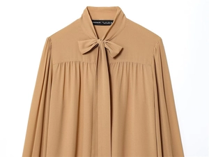 Dettaglio della camicetta in chiffon marrone con spalle a pieghe e scollatura con fiocco