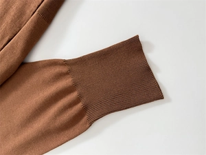 Detailed macro view of caramel brown knit sweater featuring ribbed cuffs and soft texture