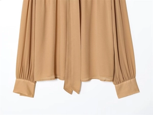 Dettaglio camicia in chiffon kaki con colletto a fiocco e polsini a pieghe