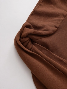 Close-up of brown knit fabric showing elegant twist knot texture and fine stitching detail
