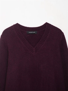 Gros plan du col en V et de la texture en maille côtelée de ce pull bordeaux