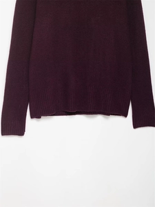 Détail d'un pull en maille violet foncé montrant l'ourlet côtelé et la texture laine
