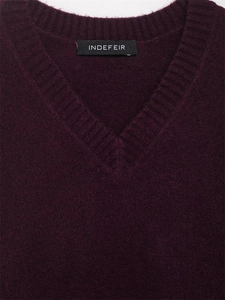 Gros plan du col en V et de l'étiquette de marque d'un pull en maille bordeaux doux