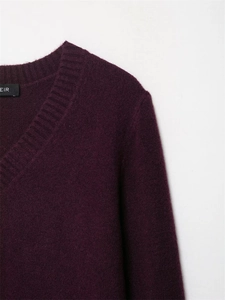 Détail du col en V et de la texture côtelée douce du pull en tricot bordeaux