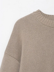Close-up of the round neck and drop shoulder detail on the taupe knit sweater fabric