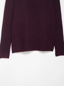 Gros plan d'un pull en maille violet foncé montrant l'ourlet côtelé et la texture douce