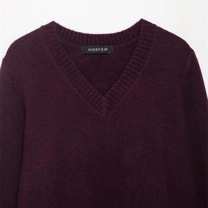 Gros plan sur un pull en maille violet foncé avec col en V et texture côtelée