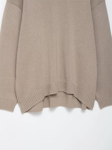 Detail of oat-colored knit sweater featuring ribbed hem and stylish side slit design