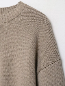 Close-up of the round neckline and cable knit texture of a khaki loose sweater