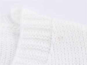 Nahaufnahme der weißen Stricktextur mit Rippstrick-Details an einem weichen Cardigan
