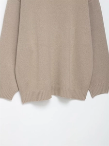 Close-up of oatmeal knit sweater showing ribbed hem and cuff texture on a white background