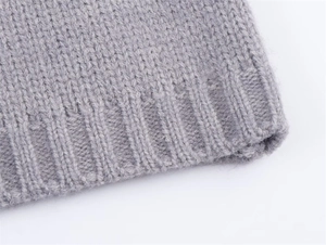 Close-up of the grey knit cardigan showing the ribbed texture and soft wool blend fabric