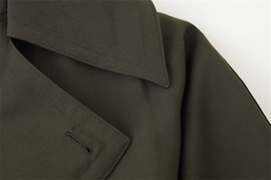 Macro detail of dark olive trench coat collar showing precision stitching and fabric texture
