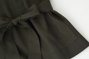 Detail of army green twill fabric coat featuring a waist belt bow and stitching pocket