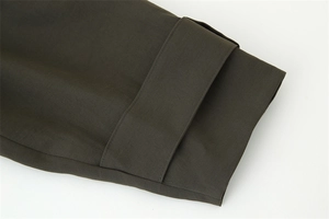 Detail of dark olive twill sleeve cuff with adjustable strap and neat stitching