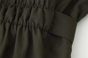 Detail of dark olive green twill fabric with elastic pleats and matching wide belt loop