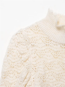 Detailansicht des Rüschenkragens und der Häkelspitzen-Struktur auf einem cremefarbenen Stricktop