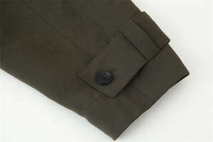 Detailed macro shot of olive green trench coat cuff with buckle and button detail