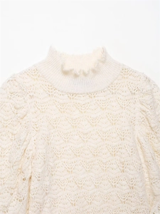 Detailaufnahme eines weißen Strickoberteils mit Rüschenkragen und floraler Spitzenstruktur