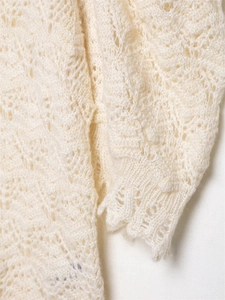 Detailaufnahme eines cremefarbenen Rippstrickpullovers mit feinem Lochmuster am Ärmel