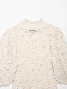 Nahaufnahme cremefarbener Strickpullover mit Ajourmuster und Rüschen am Stehkragen