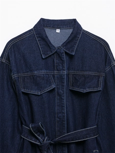 Detalle de chaqueta vaquera azul oscuro con bolsillos en el pecho y cinturón con costuras en contraste