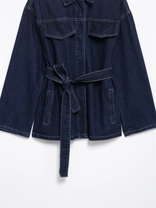 Detalle de chaqueta vaquera azul oscuro con bolsillos grandes y cinturón de lazo a juego