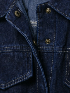 Detalle de chaqueta vaquera azul oscuro con costuras en contraste y botones de bronce vintage