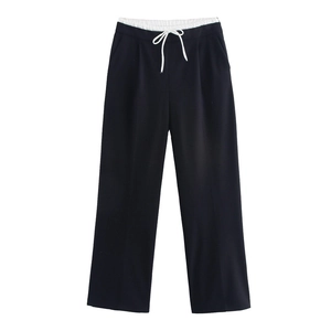 Dettaglio dei pantaloni neri a gamba larga con vita a contrasto e coulisse bianca