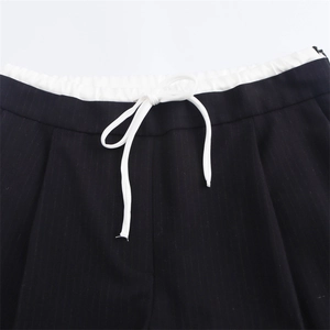 Dettaglio dei pantaloni neri a righe con cordoncino bianco e vita elastica sportiva
