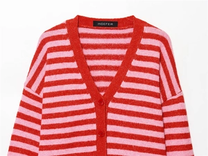 Détail d'un gilet en maille rayé à col en V avec boutons rouges et texture douce