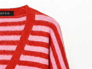 Détail de gilet rayé à col en V présentant une texture en maille pelucheuse rouge et rose