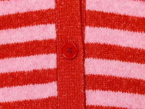Gros plan d'un bouton rouge brillant sur le tricot rayé rose et rouge du gilet