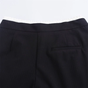 Dettaglio dei pantaloni neri gessati con elastico in vita e tasca posteriore a filo