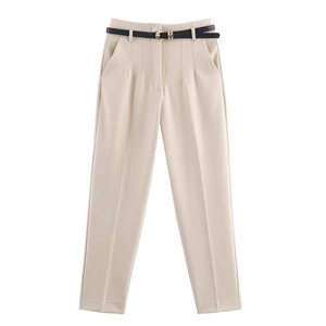 Dettaglio pantaloni beige a vita alta con cintura nera sottile e pieghe in vita