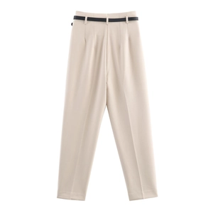 Dettaglio dei pantaloni a vita alta color crema con cintura nera e pieghe frontali