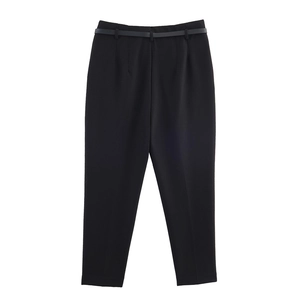 Dettaglio di pantaloni neri a vita alta con cintura sottile e piega centrale netta