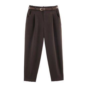 Dettaglio dei pantaloni marroni a vita alta con cintura sottile e pieghe frontali eleganti